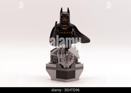 A batman lego minifigure standing on a grey brick pedestal against a white background. Stock Photo