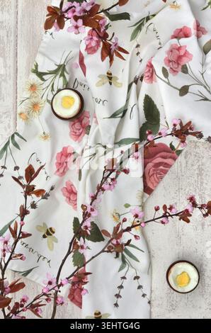 Easter table decoration with pink rose tablecloth, twigs with pink flowers. Top view photo. Stock Photo