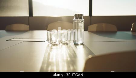 Meeting, business and glass on table in empty office for workshop, corporate and boardroom. Planning, conference and furniture with water pitcher on Stock Photo