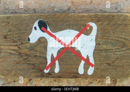 Jesus Pobre, Spain - May 17, 2026. A hand painted wooden sign shows a white dog crossed out with a red line. This sign marks a no dogs allowed area in Stock Photo