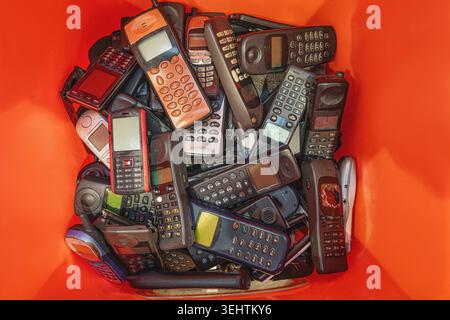 Pile of broken smartphone in a recycling container. disposing smartphone into recycling bin. Stock Photo