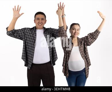Happy smiling young couple waving hands joyfully on white background Stock Photo