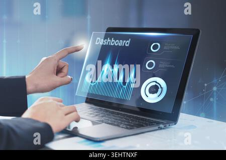 Business professional interacting with holographic data dashboard on laptop Stock Photo