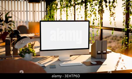Computer blank screen mockup in a modern office with sunlight, green plants, organized workspace, and natural light. Close-up front view. Stock Photo
