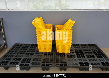 Stack of yellow plastic basket on black plastic pallet in warehouse environment conveying sense of order and organization ready for storage and transp Stock Photo
