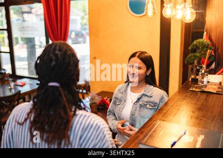 Two women having conversation at restaurant bar area Stock Photo