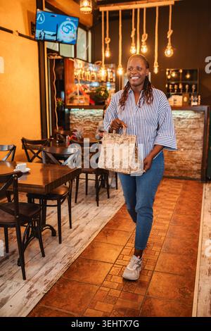 Happy woman leaving restaurant with takeout food bag Stock Photo