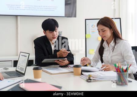 Asian business professionals discussing data in modern office meeting Stock Photo