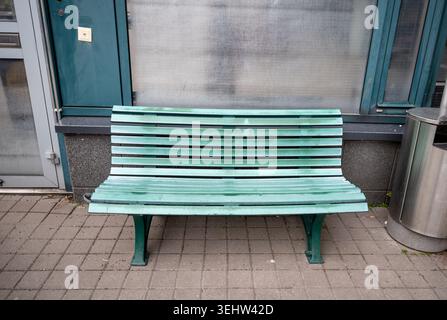 Empty green wooden bench near urban building facade in minimalist city environment Stock Photo