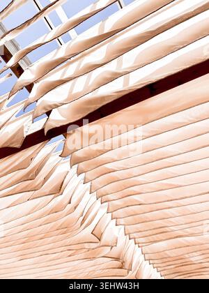 Abstract beige fabric awnings on a building facade, architectural detail with layered lines, soft shadows and warm minimalist texture Stock Photo