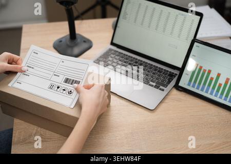 Close up logistics worker attaching barcode label on cardboard parcel in delivery service office. Concept of shipping, postal operations, startup, eco Stock Photo