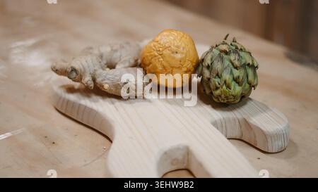 Ginger root, dried fruit, and artichoke on a wooden cutting board Stock Photo