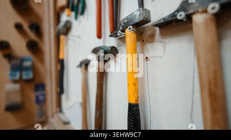 Hammers and other work tools neatly arranged on a workshop wall Stock Photo