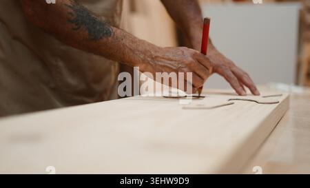 Wood artisan outlining creative design on wooden board using template and pencil Stock Photo