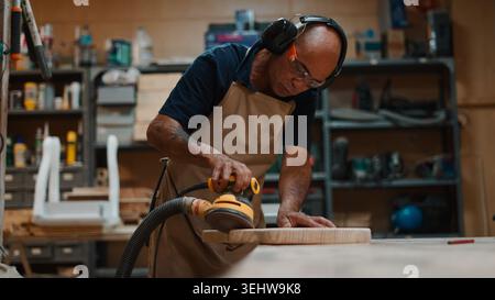 Wood artisan sanding plank in workshop, dedicated to craft and carpentry Stock Photo