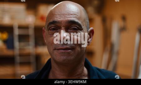 Mature craftsman smiling, working in his woodworking workshop or studio Stock Photo