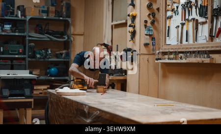 Wood artisan sanding wooden piece in workshop, crafting with skill Stock Photo