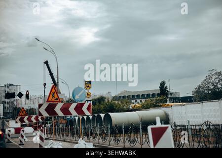 Kyiv, Ukraine - 2 May 2026. Urban infrastructure upgrade with road construction signs, utility pipes, traffic barriers under dramatic storm clouds in Stock Photo