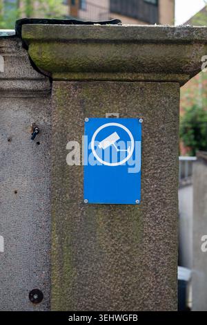 Blue surveillance camera security sign on stone wall in residential area Stock Photo