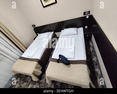 Simple standard hotel room interior featuring two single twin beds. Stock Photo