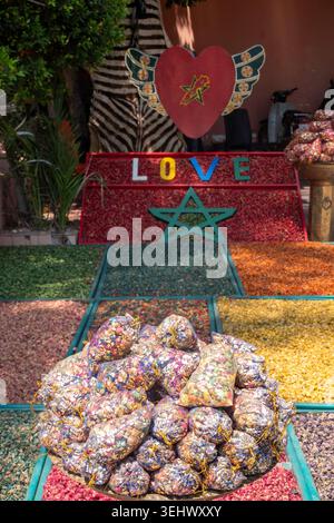 A colorful outdoor display of dried herbs, spices, and potpourri arranged in geometric patterns on the ground outside a Moroccan shop Stock Photo