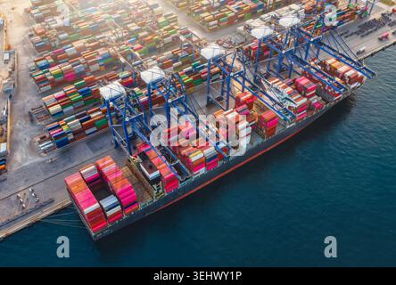 High aerial view of a docked super container cargo ship being unloaded by cranes in a commercial terminal Stock Photo