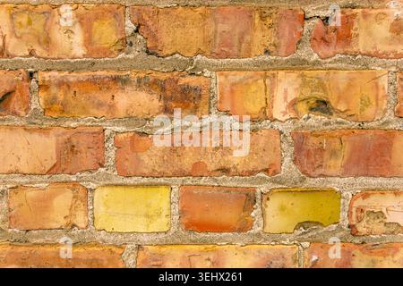 Close up view of rustic brick wall with peeling yellow paint. Stock Photo