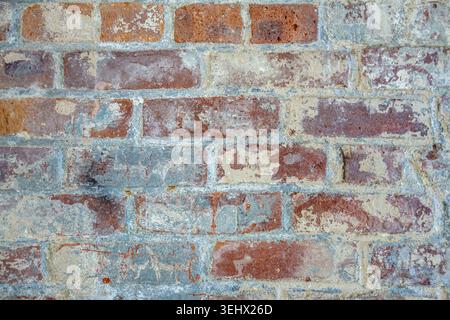 Close up view of rustic brick wall with peeling blue or teal paint. Stock Photo