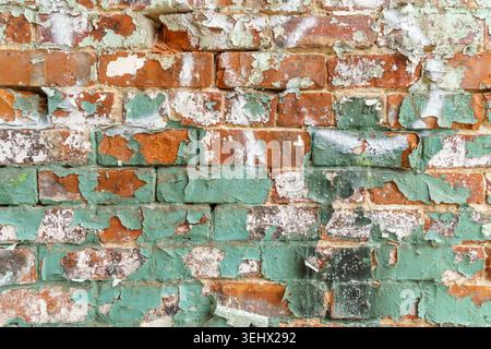 Close up view of rustic brick wall with peeling blue or teal paint. Stock Photo
