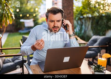 Stressed businessman having difficult phone call working outdoors Stock Photo