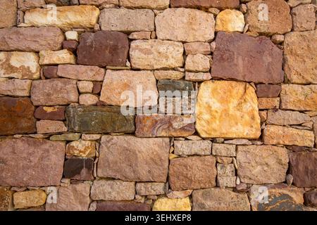 Rustic old stone wall texture with brown and yellow bricks in historical building Stock Photo