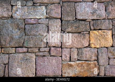 Rustic old stone wall texture with brown pink and yellow bricks in a traditional historical building Stock Photo