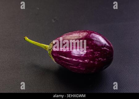Fresh, raw striped eggplants on a rustic background. This still life highlights the vibrant purple white colors of the vegetables. Ideal for healthy e Stock Photo