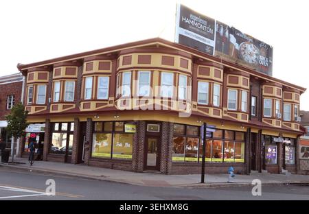 Very Decorative large two-story corner commercial building with projecting bay windows, brick lower walls, storefront windows, a rooftop billboard Stock Photo