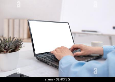 Woman typing on laptop with isolated white screen in bright office setup, suitable for software presentation, digital marketing or online business moc Stock Photo