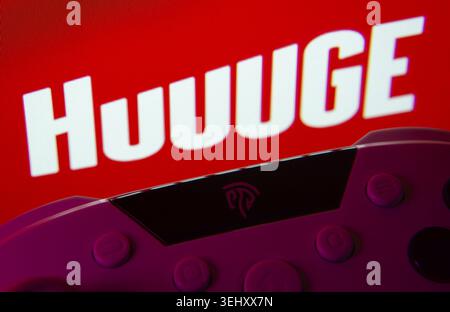 Dhaka, Bangladesh- 24 Mar 2025: A close-up of a gamepad with the Huuuge Games seen on screen in the background Stock Photo