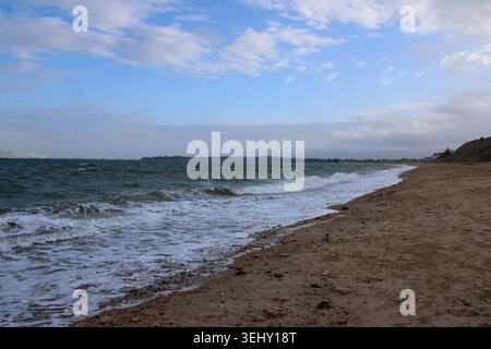 Waves rolling onto a quiet beach beneath a dramatic cloudy sky along the Dorset coastline in southern England. Stock Photo