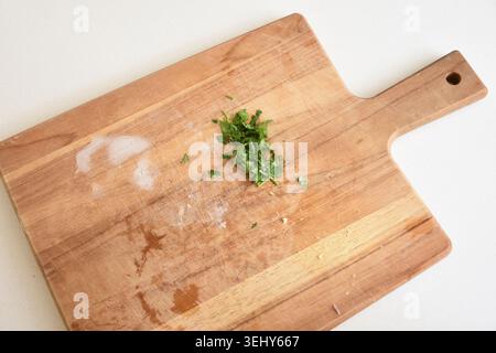 Fresh chopped cilantro on a rustic wooden cutting board, captured in natural light with vibrant green tones and a clean culinary composition. Stock Photo