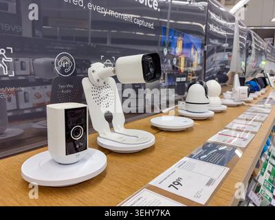 Wireless smart home security cameras and surveillance devices on display shelves in a modern electronics retail store. Stock Photo