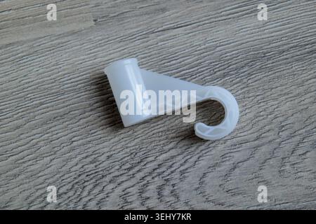 White plastic hook on wooden floor Stock Photo