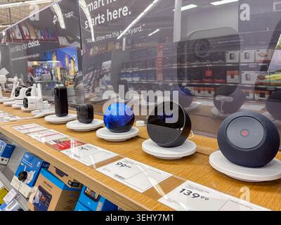 Retail display featuring smart home speakers, alarm clocks, and security cameras for sale in an electronics store. Stock Photo
