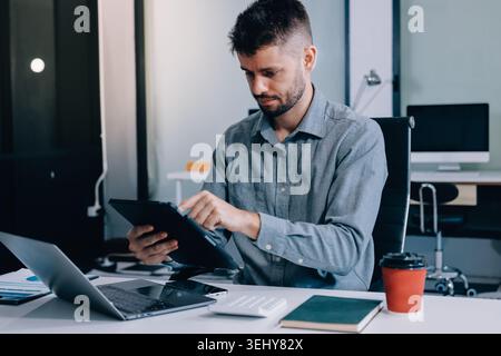 Tired worker. A tired businessman works in the evening. A man in office clothes is holding his temples. Problems in business. The businessman is tryin Stock Photo