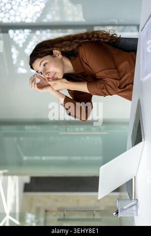 Confident Latina business woman pointing at a flipchart board during a presentation, explaining marketing strategy and leading a training seminar in office. Stock Photo