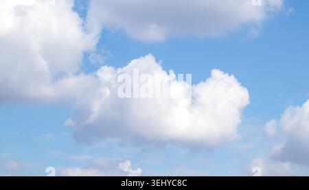 Fluffy white cloud floating in a bright blue sky over a calm summer atmosphere Stock Photo