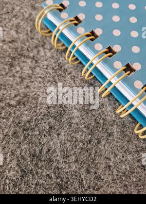 Blue spiral-bound notebook featuring white polka dots lying on a textured gray background, symbolizing ideas, studying, creativity, and planning Stock Photo
