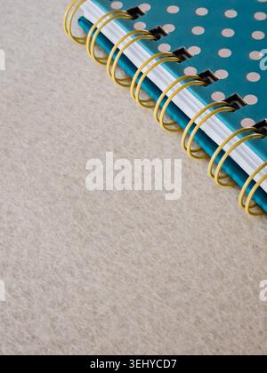 Teal polka dot notebook with gold spiral binding in the upper right corner, resting on textured light beige surface with ample copy space Stock Photo