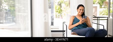 Woman relaxing on chair and using smartphone Stock Photo