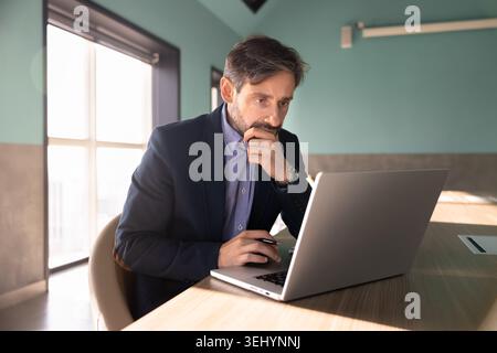 Businessman using laptop, focused on data analysis, searching problem solution Stock Photo