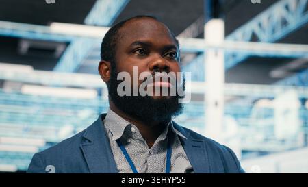 Server farm employee putting on VR headset to do network management. Data center system administrator uses virtual reality simulation to oversee infrastructure rigs, camera B Stock Photo