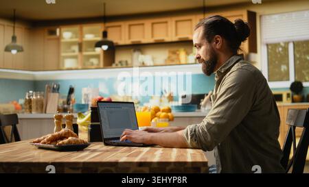 Software developer at home, writing code and debugging applications, IT engineering on command-line interfaces. Focused digital work ensures software maintenance, laptop in the kitchen. Stock Photo